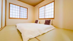 a bedroom with a large white bed with two windows at 東京雷門ー千の森Asakusa in Tokyo