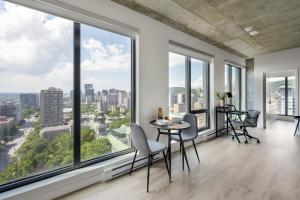 an empty living room with large windows and a table and chairs at Appartements Dorchester in Montreal