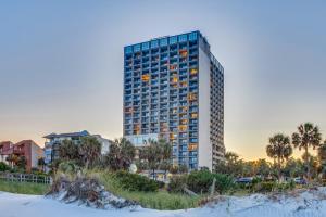 een hoog gebouw met palmbomen ervoor bij Ocean Forest Plaza Condos in Myrtle Beach