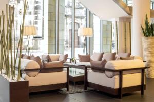 a lobby with couches and a table and windows at NH Collection Dresden Altmarkt in Dresden +45 photos