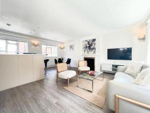 a living room with a white couch and a tv at Split Level 2 Bed Apartment- Mayfair in London