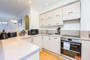 a kitchen with white cabinets and a stove top oven at Split Level 2 Bed Apartment- Mayfair in London
