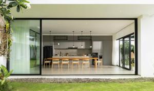 an open kitchen and dining room with large glass doors at Arita Villa Canggu by Nakula in Canggu