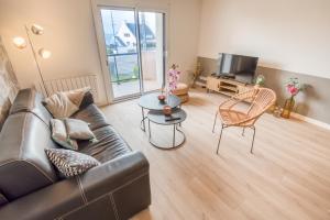 a living room with a couch and a table and a tv at Elégant Appartement 2 chambres bord de mer par Groom in Ploemeur