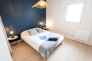 a bedroom with a bed with a blue accent wall at Elégant Appartement 2 chambres bord de mer par Groom in Ploemeur