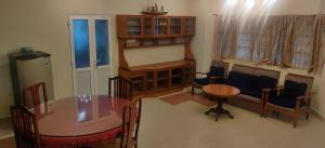 a living room with a table and chairs and a desk at Coral Shelters Service Apartments Thuvariman in Madurai +19 photos
