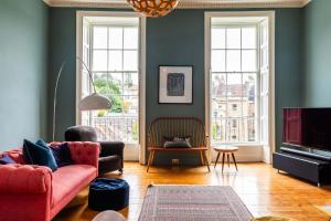 a living room with a red couch and two windows at Grand Georgian Townhouse with Garden in Bath