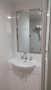 
a white sink sitting under a mirror in a bathroom at Ambassador Motel in Rockhampton
