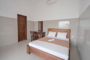 a bedroom with a bed and a desk in it at Rommeo Inn Lovina Mitra RedDoorz in Temukus