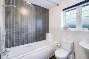 a bathroom with a tub and a toilet and a sink at Modern Comfort 4 Bedroom, 3 Bath House in Maidenhead in Maidenhead +37 photos
