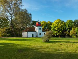 a white house with a red roof in a field at Ferienwohnung Erika in Gollwitz