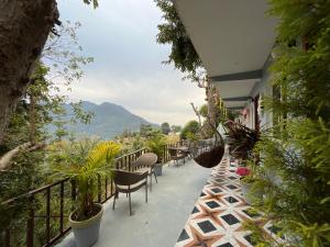a balcony of a building with chairs and plants at Kyarki Village Homestay & Cafe in Rishīkesh