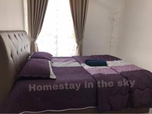 a bed with a purple comforter with the wordsharnessplay in at Puncak Alam Homestay in Kampong Bukit Hijau