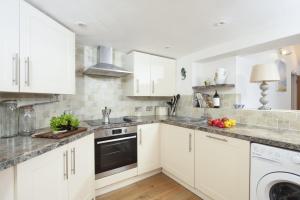 a white kitchen with white cabinets and a dishwasher at Samson Cottage in Saint Mawgan