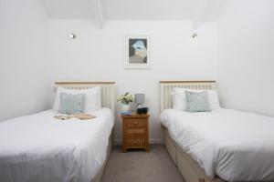 two twin beds in a room with a night stand at Samson Cottage in Saint Mawgan