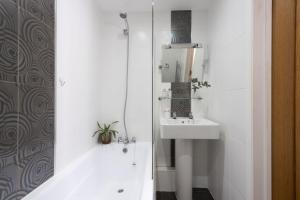 a white bathroom with a sink and a shower at Samson Cottage in Saint Mawgan