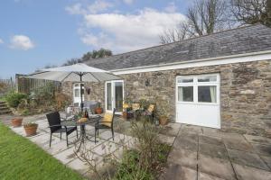a patio with an umbrella and a table and chairs at Samson Cottage in Saint Mawgan