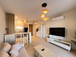 a living room with a couch and a large television at Stylish 1BR Ground With Free Pool & Lagoon Access In Gouna in Hurghada