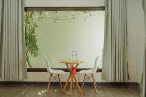 a table and two chairs in front of a window at Homestay Hơ Đơng in Pleiku