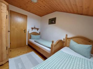 a bedroom with two beds and a wooden ceiling at Wörle, Ferienhof in Halblech
