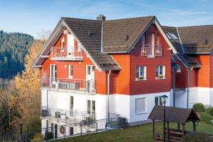 een oranje en wit huis met een balkon bij Ferienwohnung Tannenblick 4-3 in Oberhof