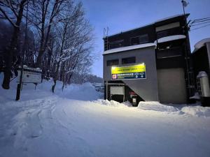 un edificio con un cartello nella neve di Snow Resort Hermitage a Asahikawa
