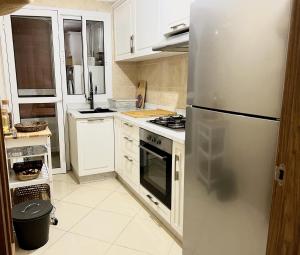 a kitchen with a stainless steel refrigerator and white cabinets at Appartement Kawacim in Tangier