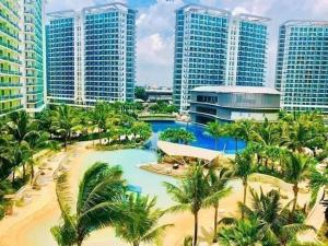 a resort with a pool and palm trees and buildings at Metro Manila Cityscape Charm at Azure Urban Resort Paranaque near NAIA Airport in Manila