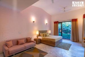 a bedroom with a bed and a couch at StayVista at The Manvi Estate - Pool, WiFi & Bonfire in Bahora