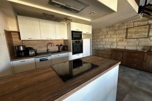 una cucina con armadi bianchi e un muro in pietra di Maisonnette de Plage sur les Toits Appart 1 chambre 1 mezzanine avec Vue a Le Grau-du-Roi