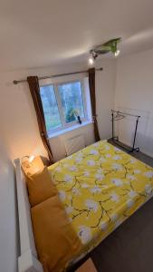 Un dormitorio con una cama amarilla y una ventana. en Pine tree House, en Mile End
