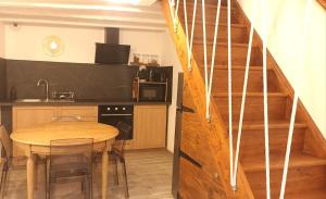 a kitchen with a wooden table and a staircase at La petite maison des choux in Les Choux