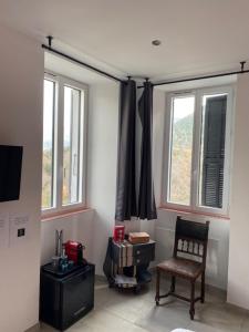 a living room with a chair and two windows at Le Relais des cols 5 Strada di PALLECA 20148 COZZANO in Cozzano