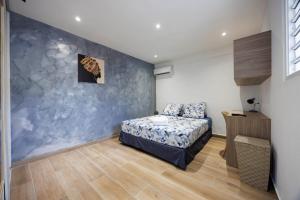 a bedroom with a bed and a blue wall at Villa Les Pierres Précieuses in Rémiré