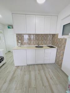 a kitchen with white cabinets and a sink at Luka MonteVilla in Bar