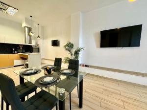 a dining room table with chairs and a television on a wall at Encanto Mediterráneo en Alicante in Alicante