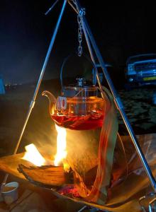 a tea kettle hanging over a campfire at night at Star sands camps in Al Raka