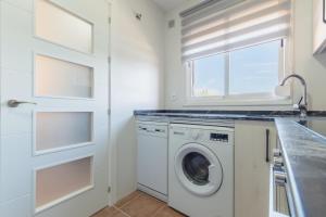 a white laundry room with a washer and dryer at Urbanización Jardín del Golf 1 in Novo Sancti Petri