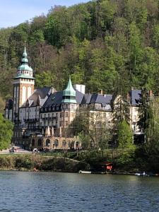 a large building with a clock tower next to a lake at Panoráma Apartman Felsötárkány in Felsőtárkány