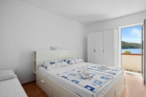 a white bedroom with a large bed and a window at Apartments Emily in Kampor