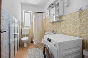 a washing machine in a bathroom with a toilet at Apartments Emily in Kampor