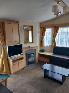 Una sala de estar con un sofá azul y una chimenea. en Chapel St leonards Happydays beachfield, en Skegness