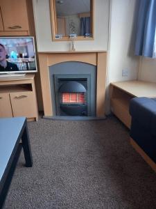Una sala de estar con chimenea y televisión. en Chapel St leonards Happydays beachfield, en Skegness