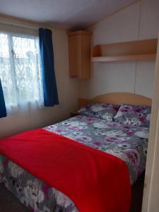 Un dormitorio con una cama con una manta roja y una ventana. en Chapel St leonards Happydays beachfield, en Skegness