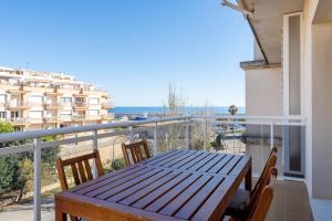 a wooden table on a balcony with a view of the ocean at Hauzify I Apartament Riba Aurea in L'Ametlla de Mar