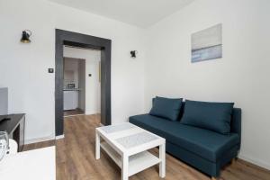 un soggiorno con un divano blu e un tavolo di Wyjątkowe Jasne Studio w Centrum Poznania by Noclegi Renters a Poznań