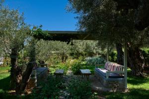 two benches sitting under a pergola in a garden at Kastro Suites in Lefkada