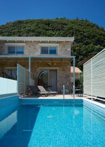 a villa with a swimming pool in front of a house at Kastro Suites in Lefkada