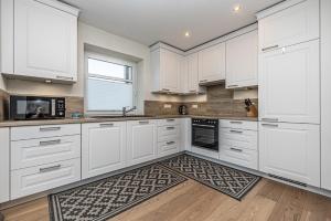 una cucina bianca con armadi bianchi e un tappeto di Ferienwohnung Luv a Gelting