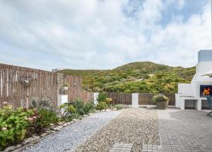 a garden with a fence and a fireplace at Kaalvoet Self-Catering Apartments in Yzerfontein